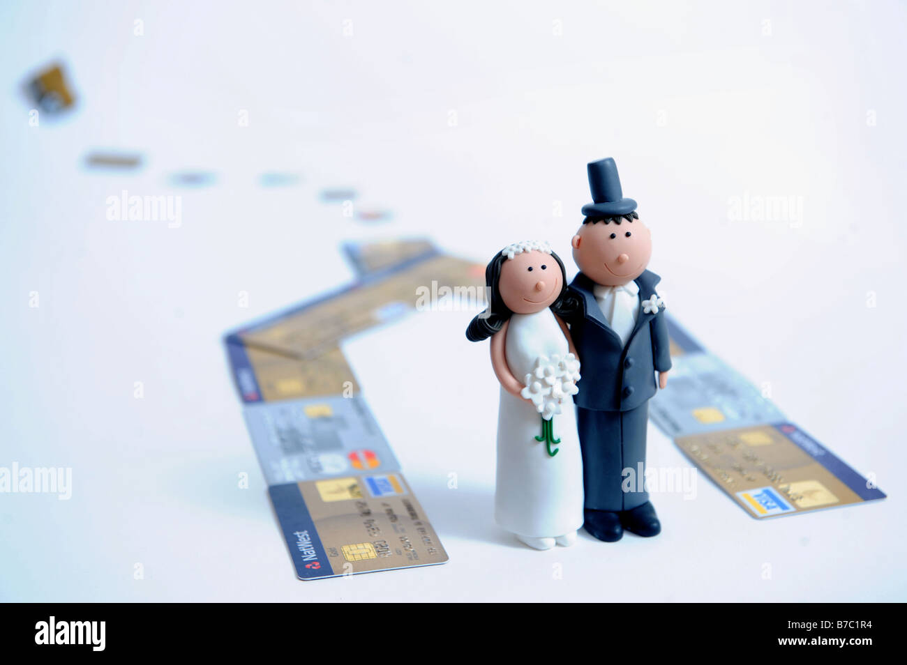 COMIC BRIDE AND GROOM FIGURES FOR DECORATING A WEDDING CAKE PICTURED AS IF LIVING IN A CREDIT CARD HOUSE Stock Photo