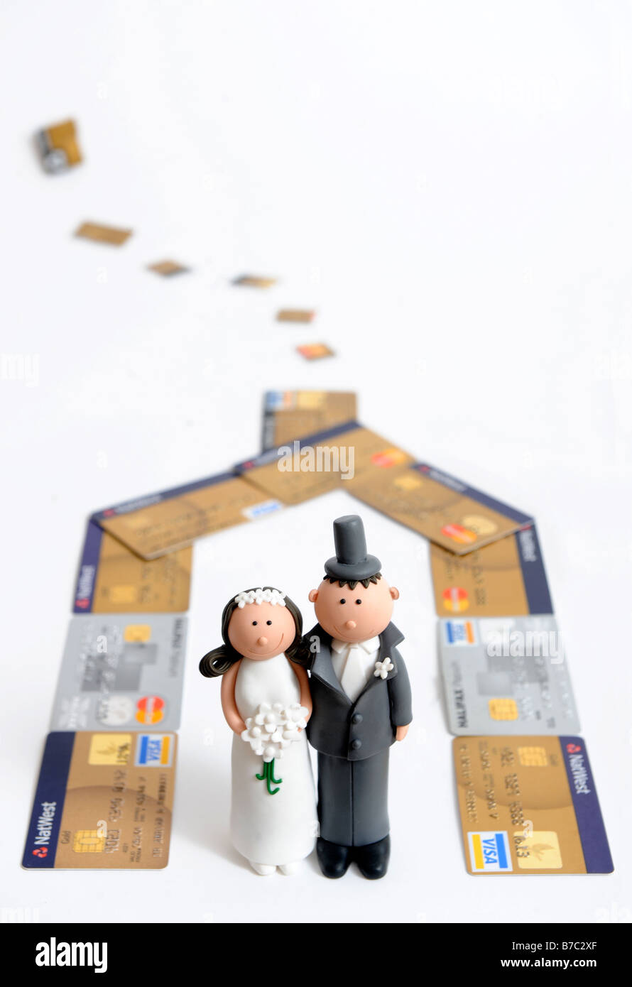 COMIC BRIDE AND GROOM FIGURES FOR DECORATING A WEDDING CAKE PICTURED AS IF LIVING IN A CREDIT CARD HOUSE Stock Photo