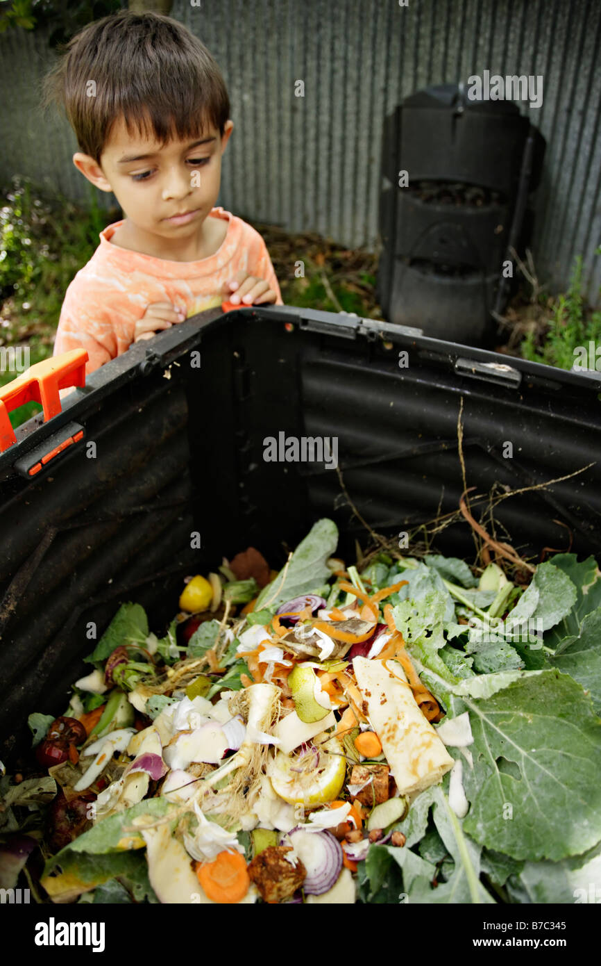 Six year old boy looks into compost bin in garden Stock Photo