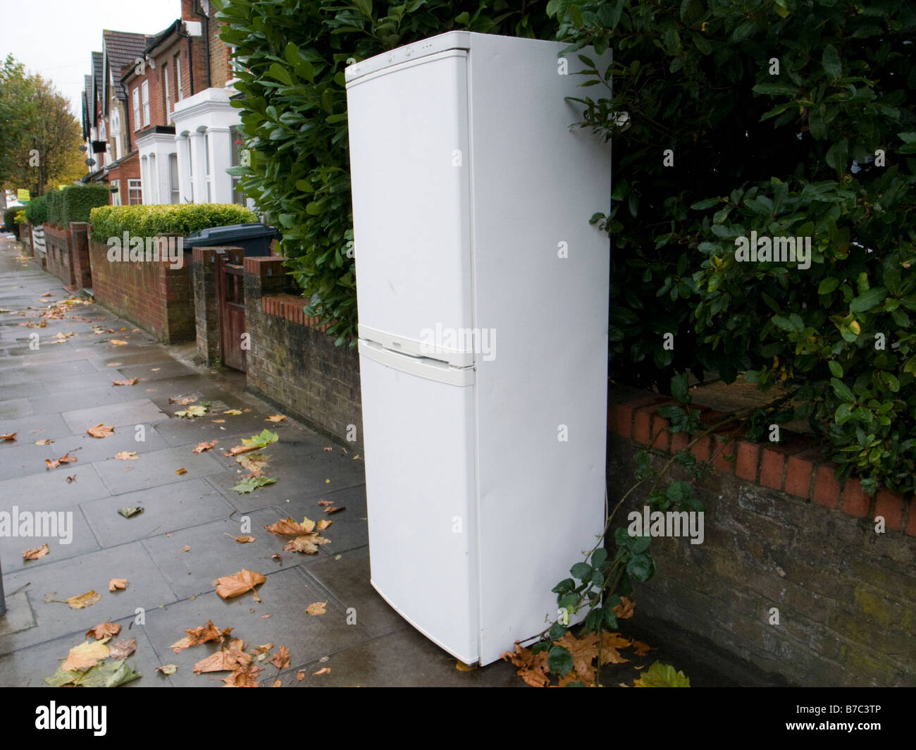 Discarded fridge freezer on pavement outside house London England UK Stock Photo