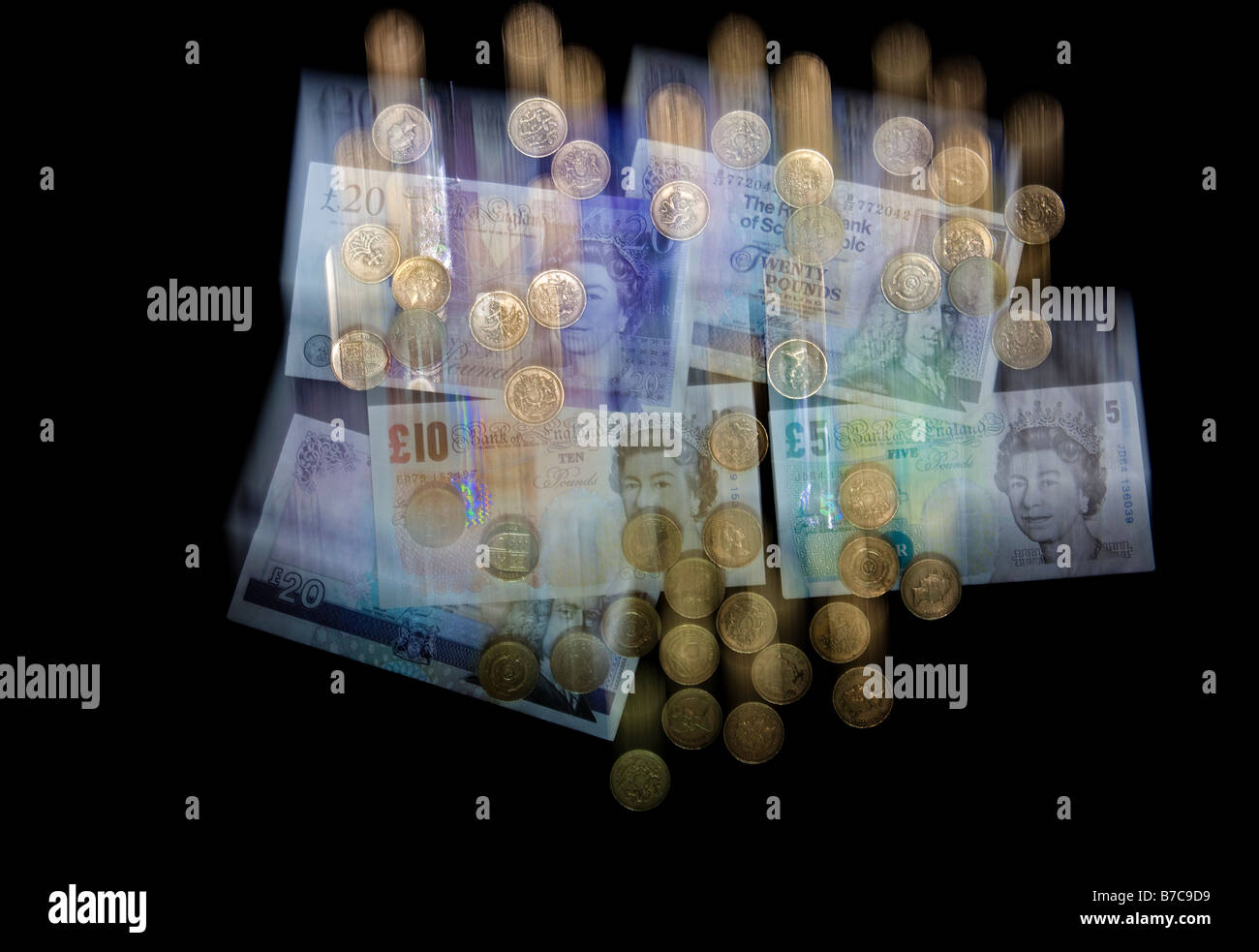 Falling blurred UK currency money, banknotes and pound coins sterling to illustrate the falling pound Stock Photo