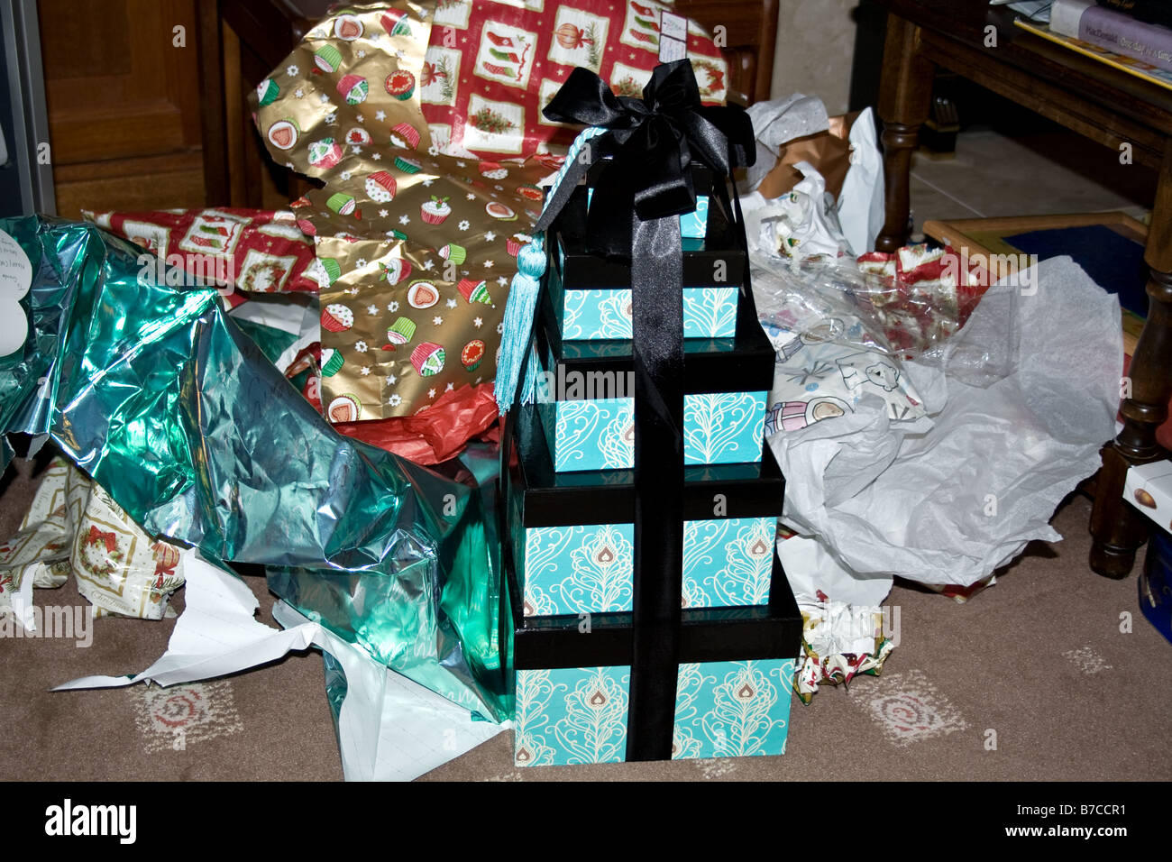 Christmas gift boxes in a stack in front of wrapping paper from opened presents Stock Photo