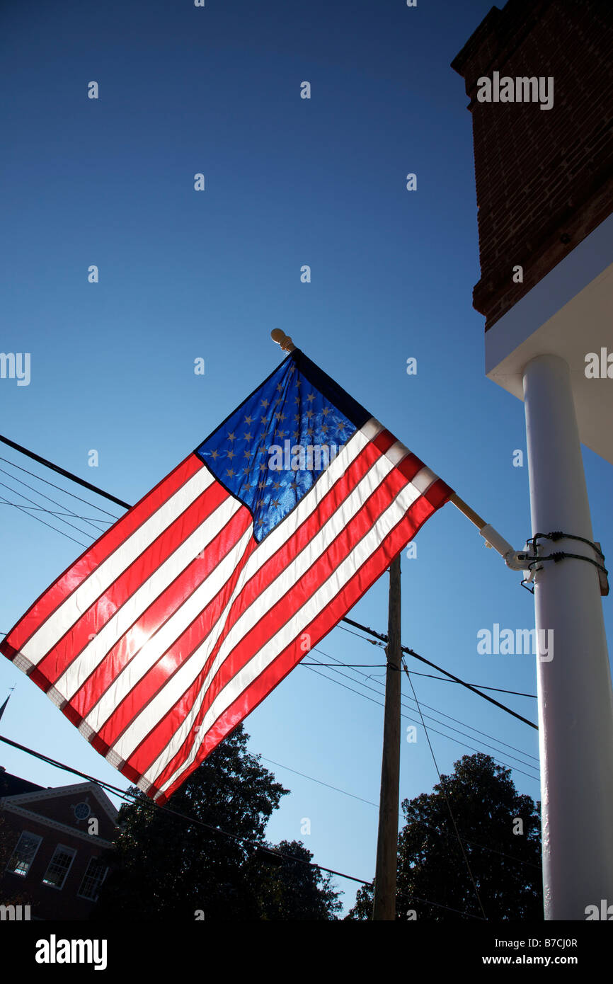 The American flag hangs proudly with a blue sky background on Main Street in Hometown America Stock Photo