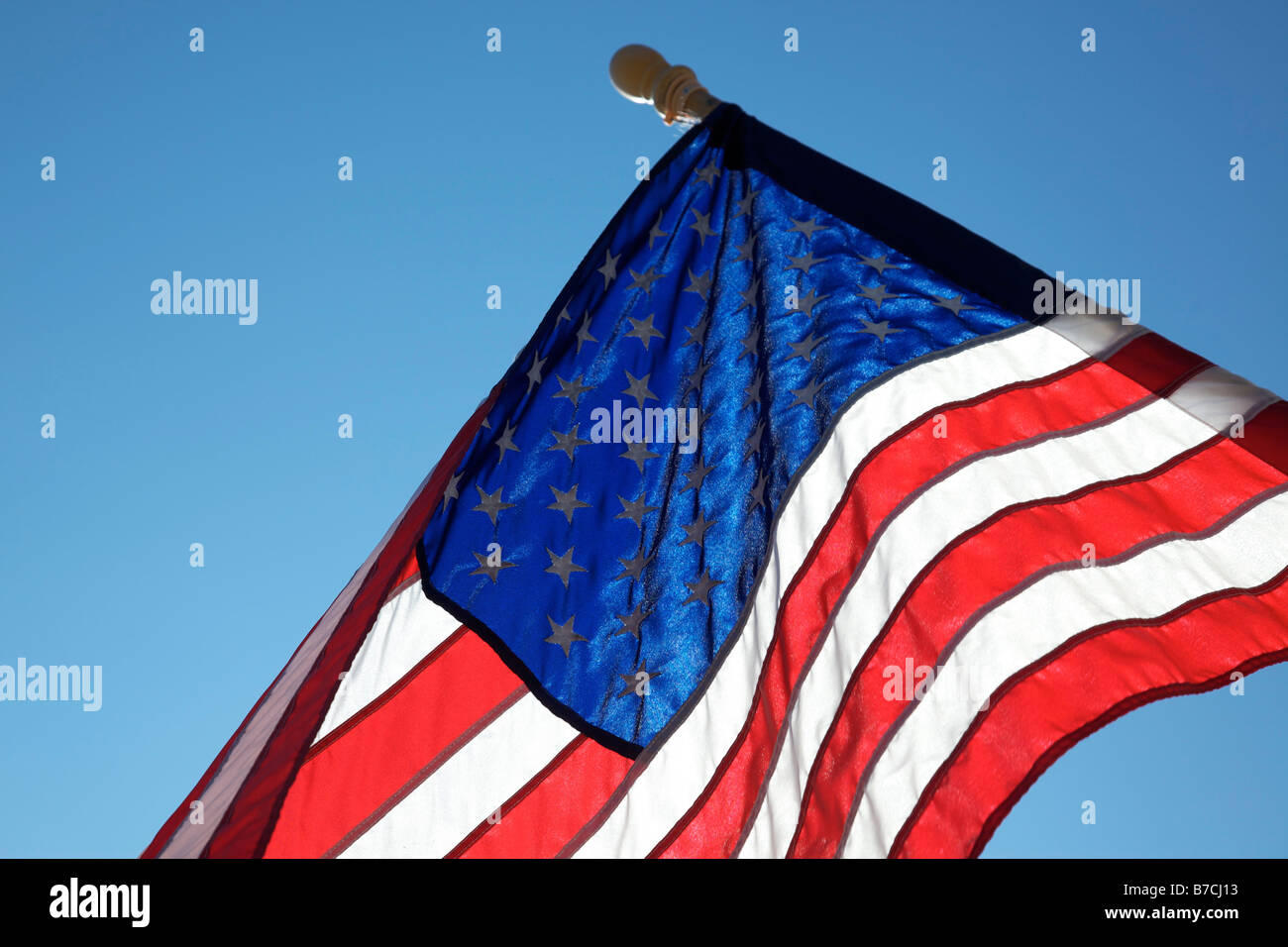 The American flag hangs proudly with a blue sky background on Main Street in Hometown America Stock Photo