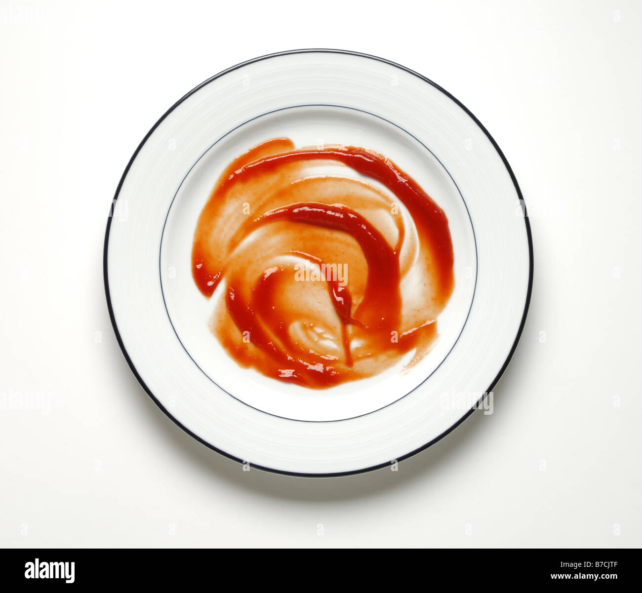Red ketchup smeared on a round dinner plate Stock Photo