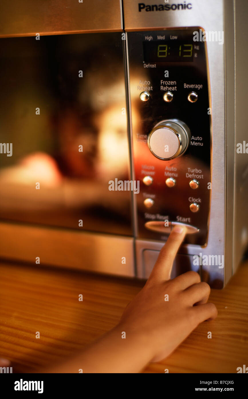 Six year old boy uses microwave oven Stock Photo