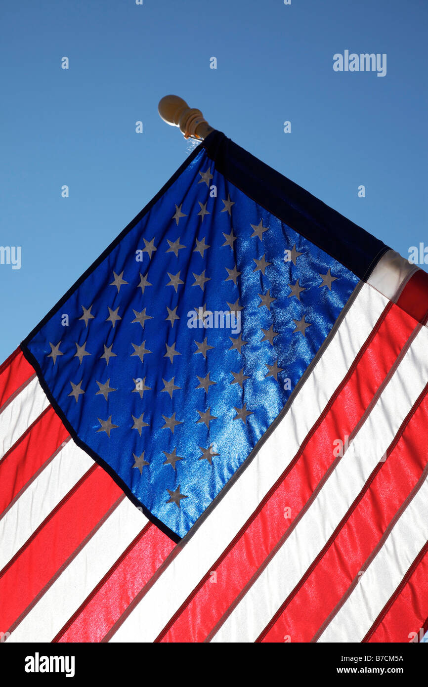 The American flag hangs proudly with a blue sky background on Main Street in Hometown America Stock Photo