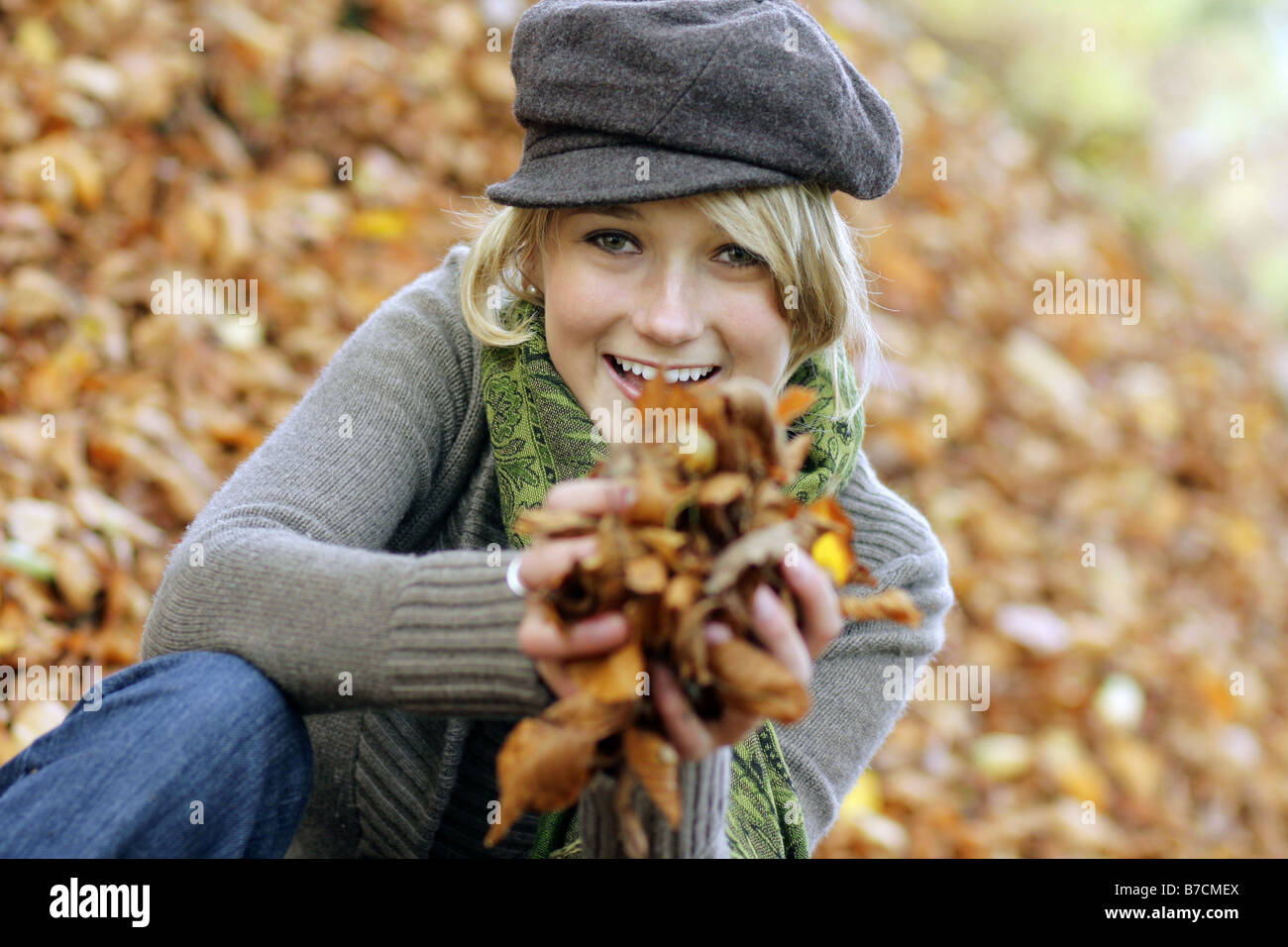 young blond woman enjoying a sunny autumn day, playing with autumn foliage, Germany Stock Photo