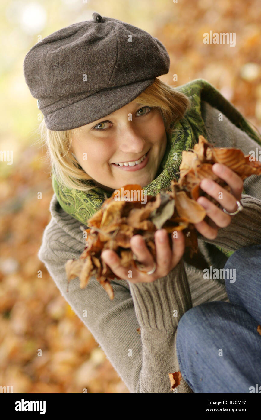 young blond woman enjoying a sunny autumn day, playing with autumn foliage, Germany Stock Photo