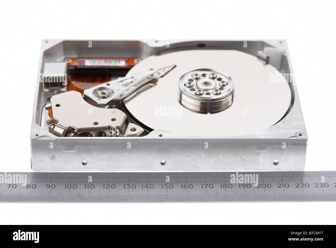 open computer hard drive on a white background next to a steel metal metric ruler Stock Photo