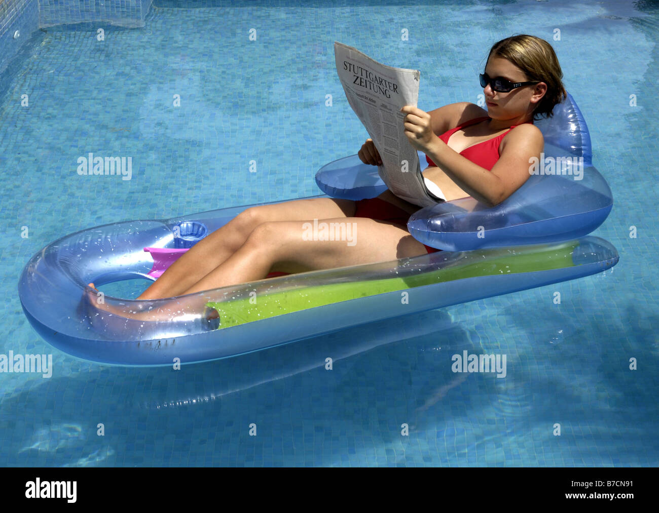 young woman on air bed reading a newspaper Stock Photo