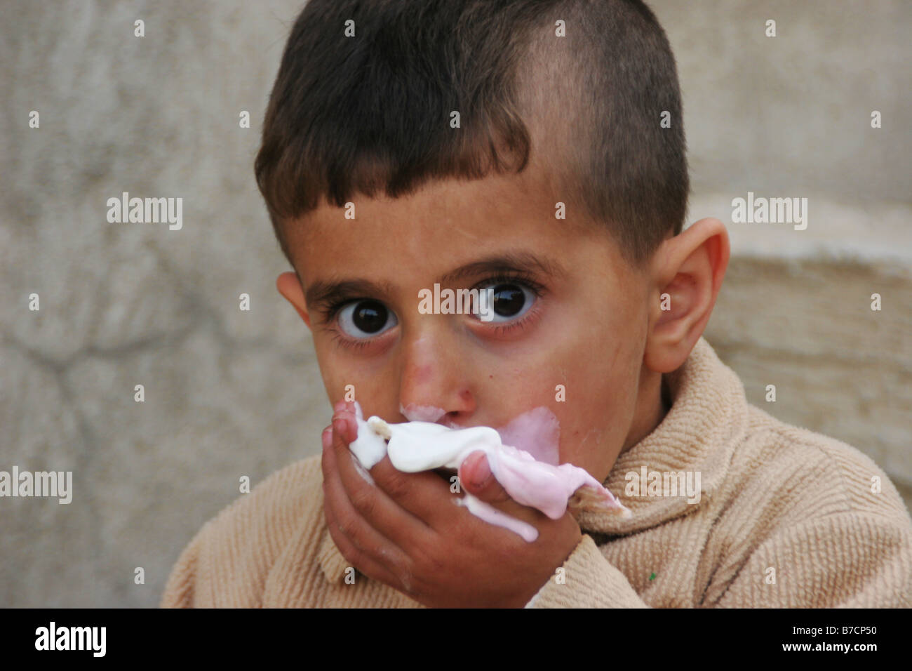 Kurdish boy eating ice cream and with dirty hands cleaning his smouth, Iraq, Iraqi Kurdistan, Sulaimaniyya, Sulaymaniyah Stock Photo