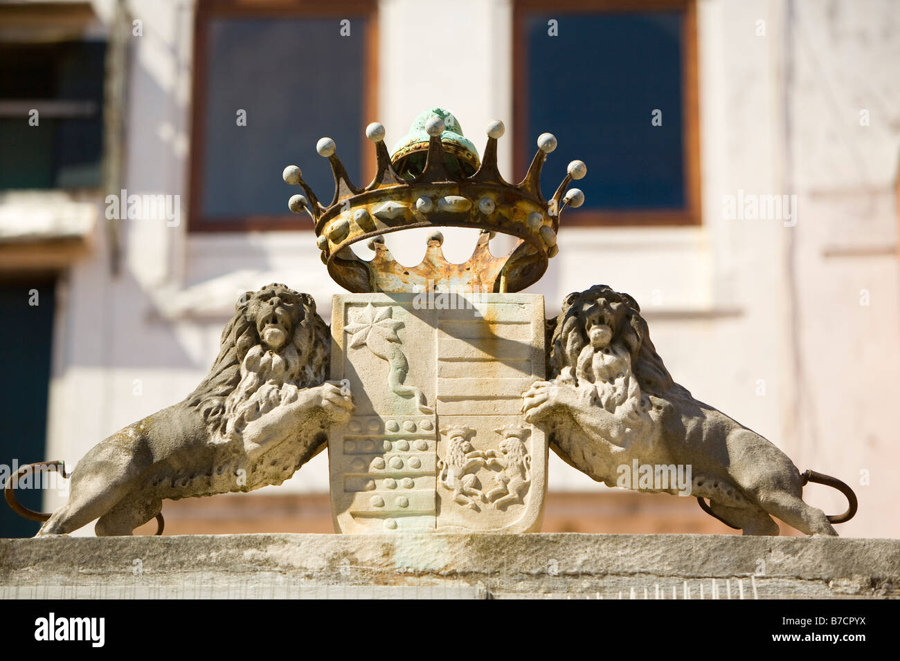 A metal Doge's crown, two Venetian lions and a shield adorn a building ...