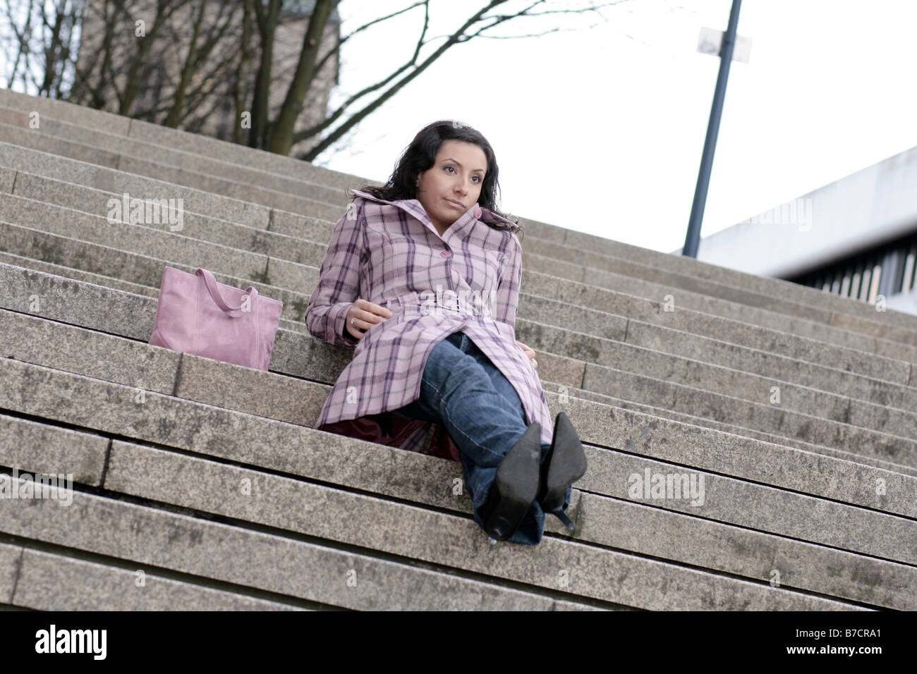 young darkhaired, bored woman sitting on stairs, waiting for her date Stock Photo