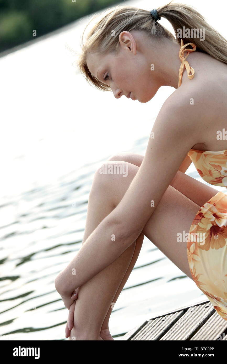 young blond, woman sitting on a landing stage Stock Photo