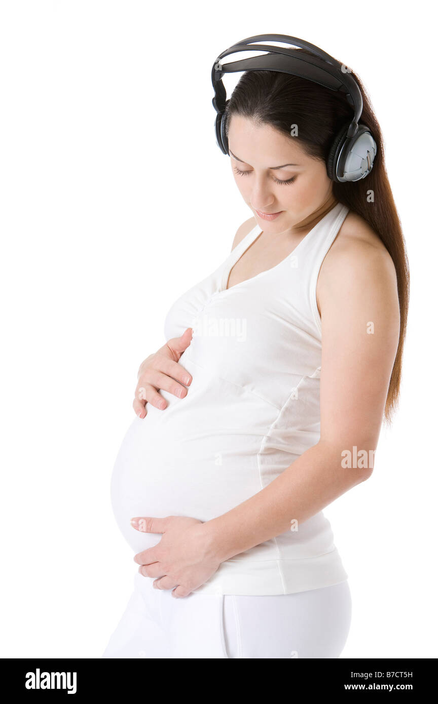 Pregnant young woman wearing a headset hands around abdomen Stock Photo