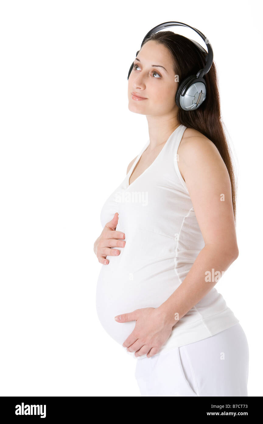 Pregnant young woman wearing headphones hands around the abdomen looking up Stock Photo