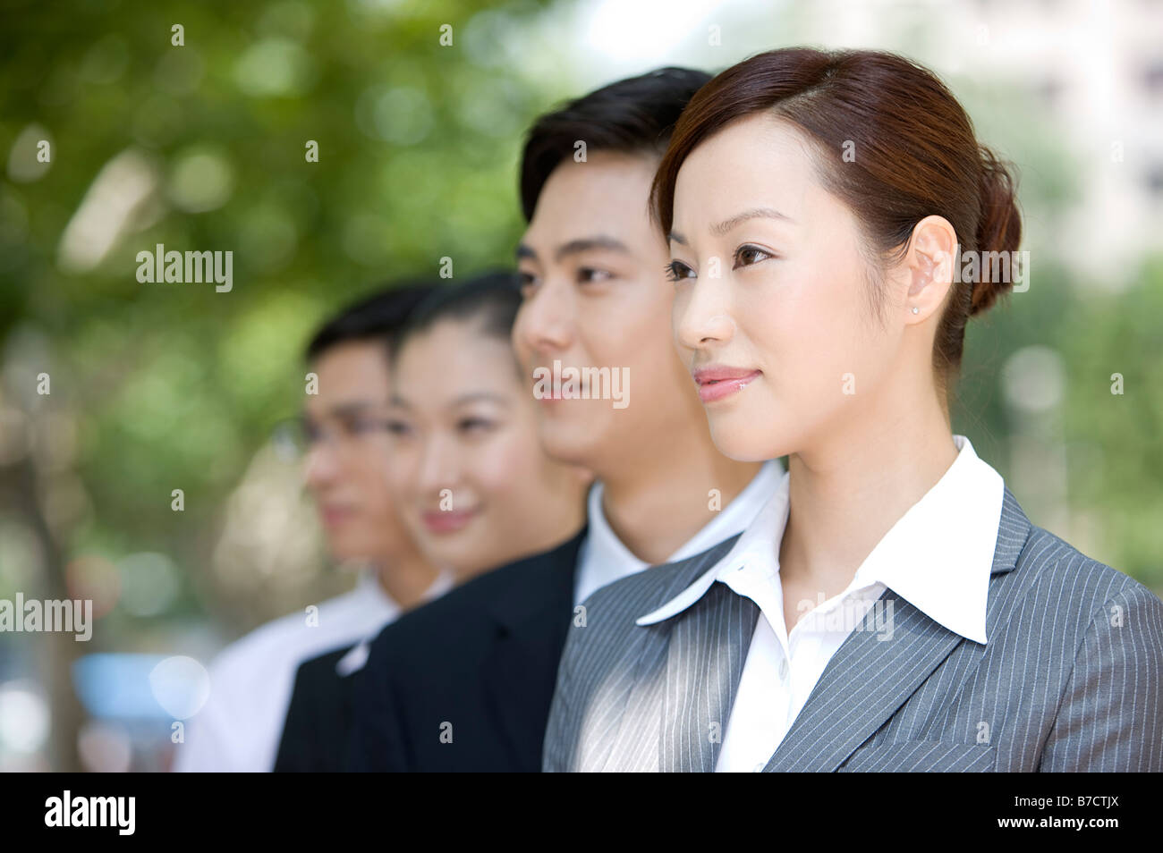 Four business people looking away and smiling in a row Stock Photo - Alamy