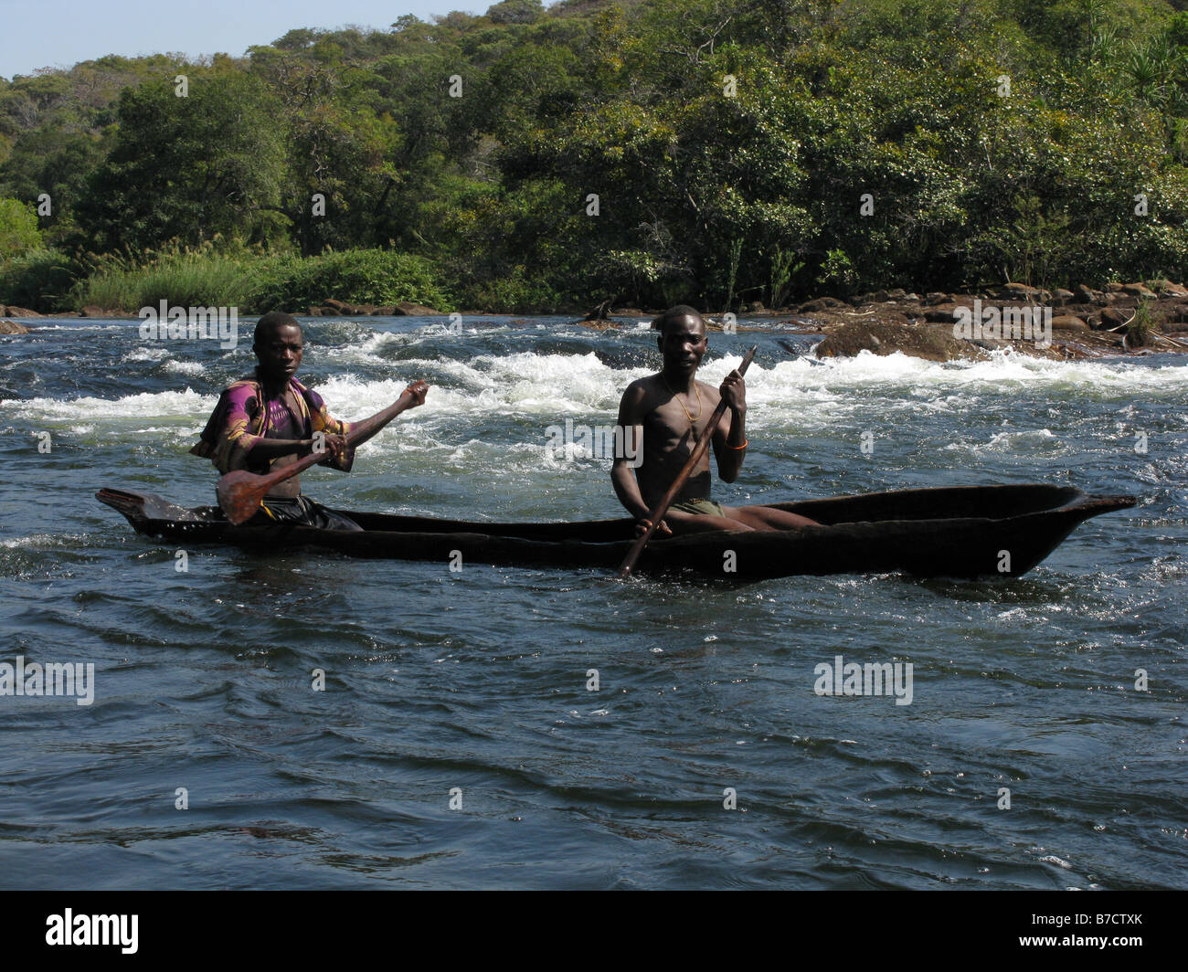 Two Congolese fishermen in dug out canoe negotiate rapids on Luapula