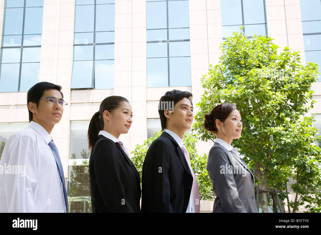 Four business people standing in a row side view Stock Photo - Alamy