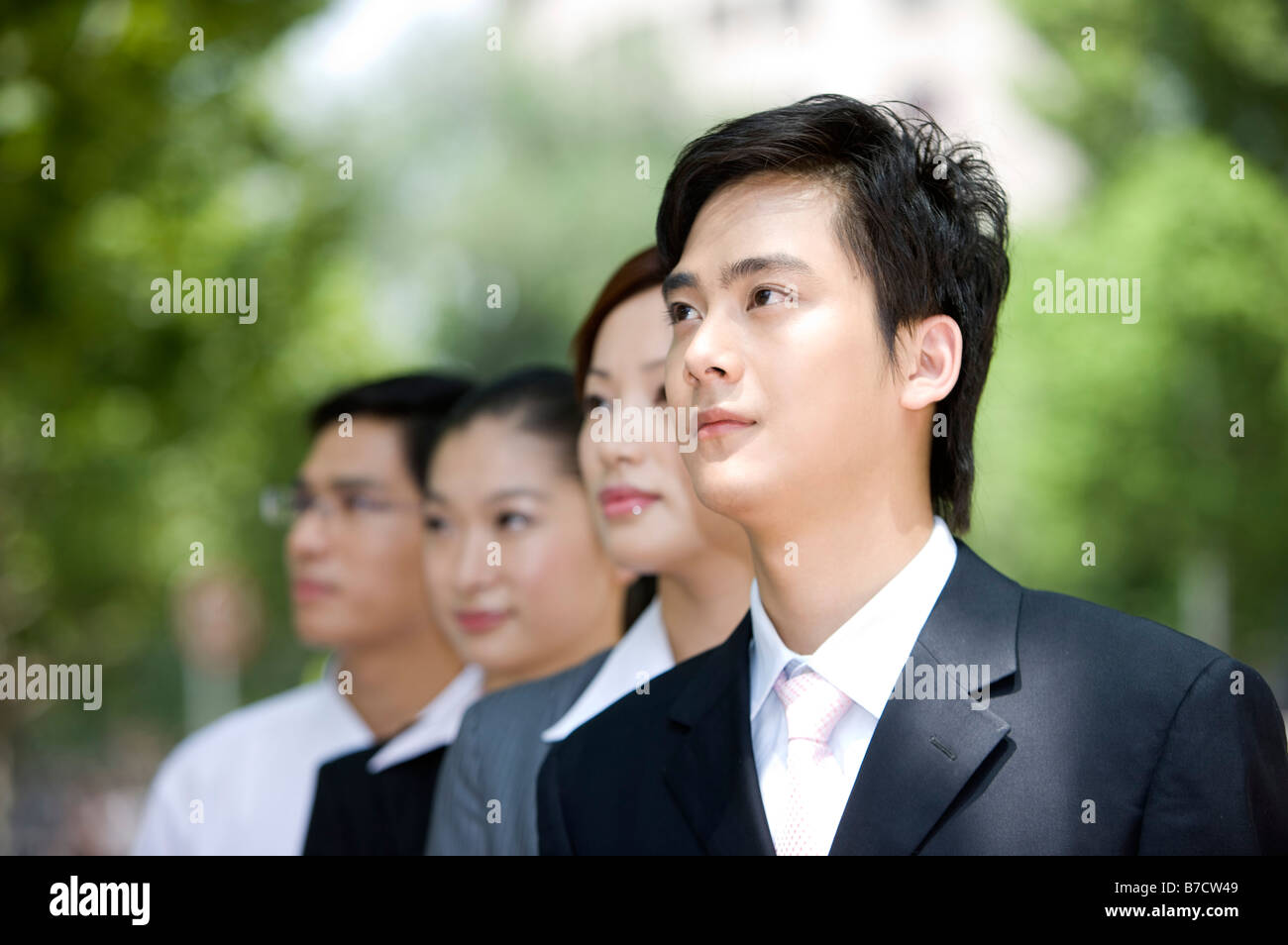 Four business people standing in a row and looking away Stock Photo - Alamy
