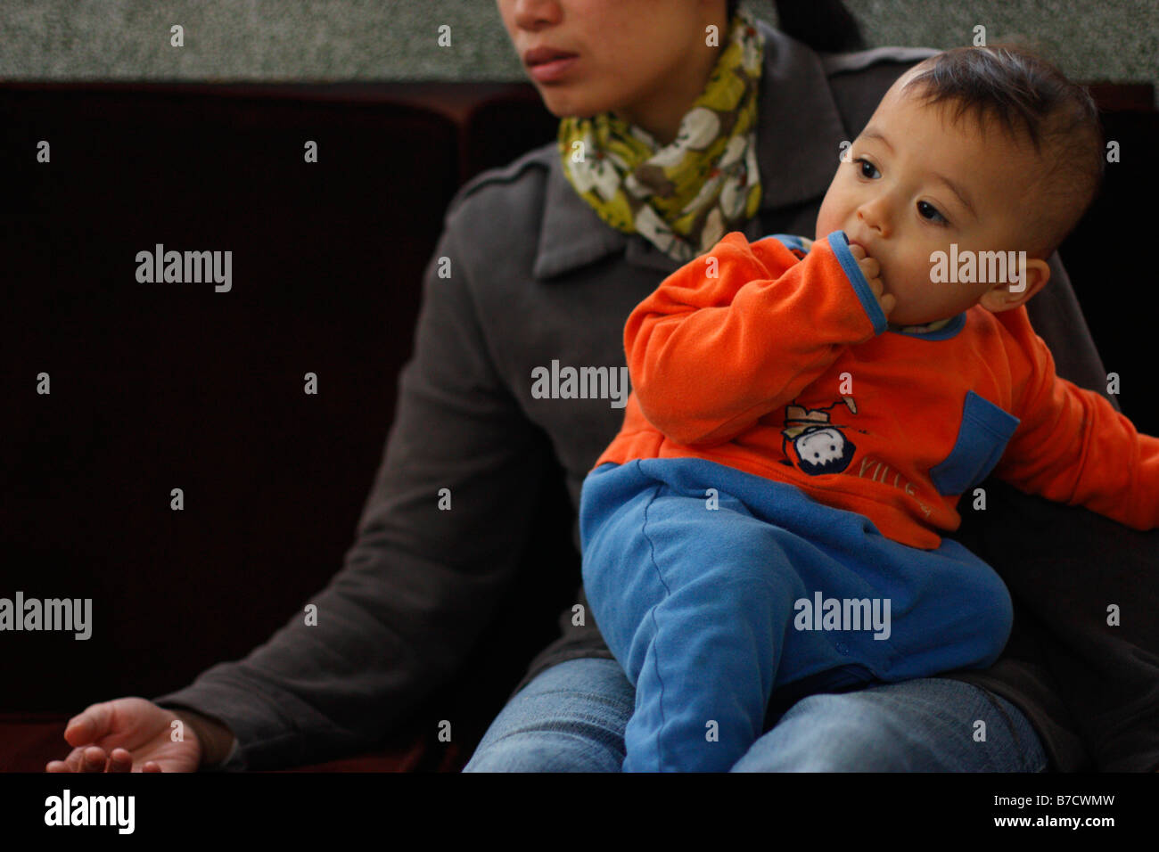 Toddler sitting on mother's lap and listening to the conversation. Stock Photo