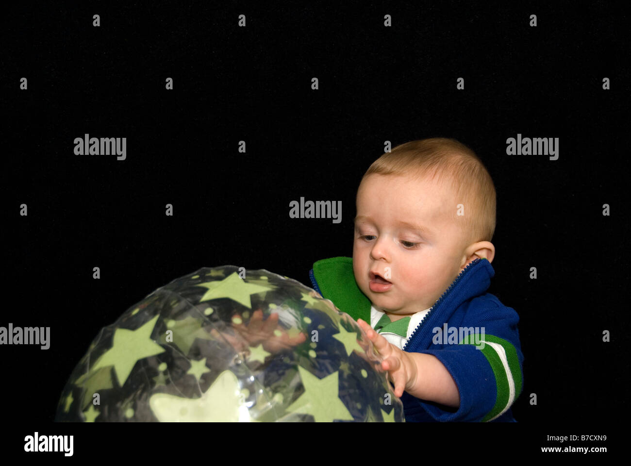 Baby Boy Playing with Ultra Violent Reflective Toys in Dark of Surestart Sensory Play Room, Sheffield, England Stock Photo