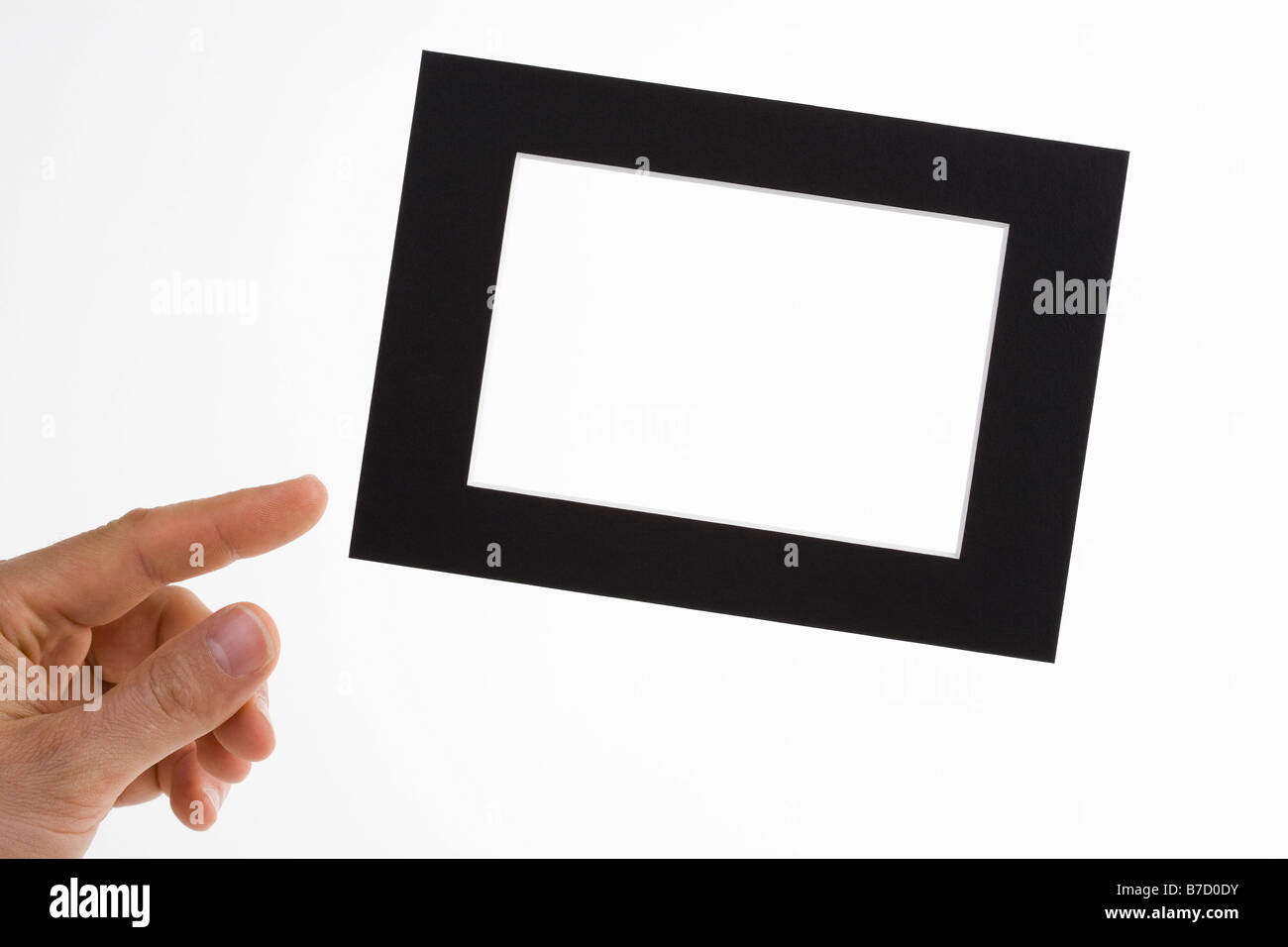 A human hand adjusting a slanted picture frame Stock Photo