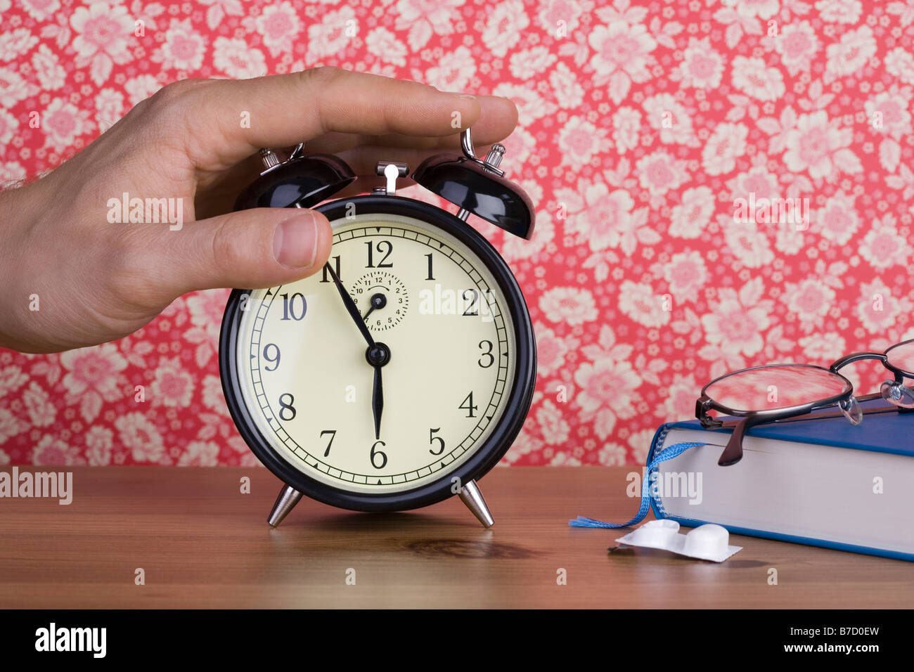 A human hand pressing an old-fashioned alarm clock Stock Photo - Alamy