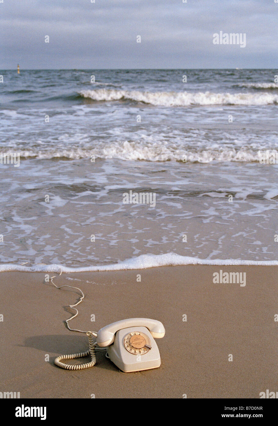 A rotary telephone on a beach at the water's edge Stock Photo