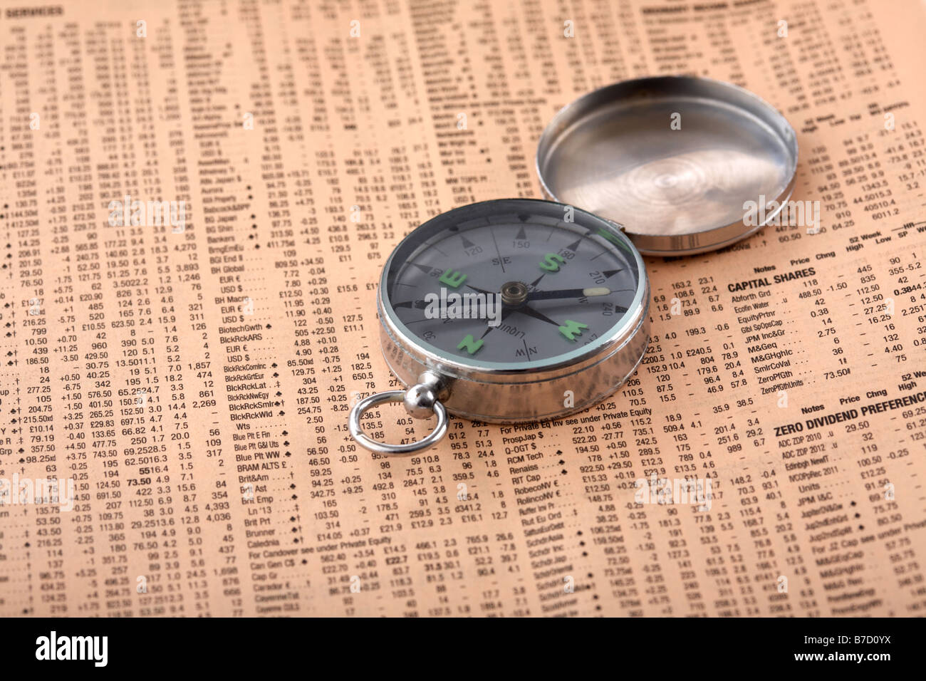 open magnetic compass sitting on a copy of the financial times concept of being lost or seeking or following direction in the stock markets Stock Photo
