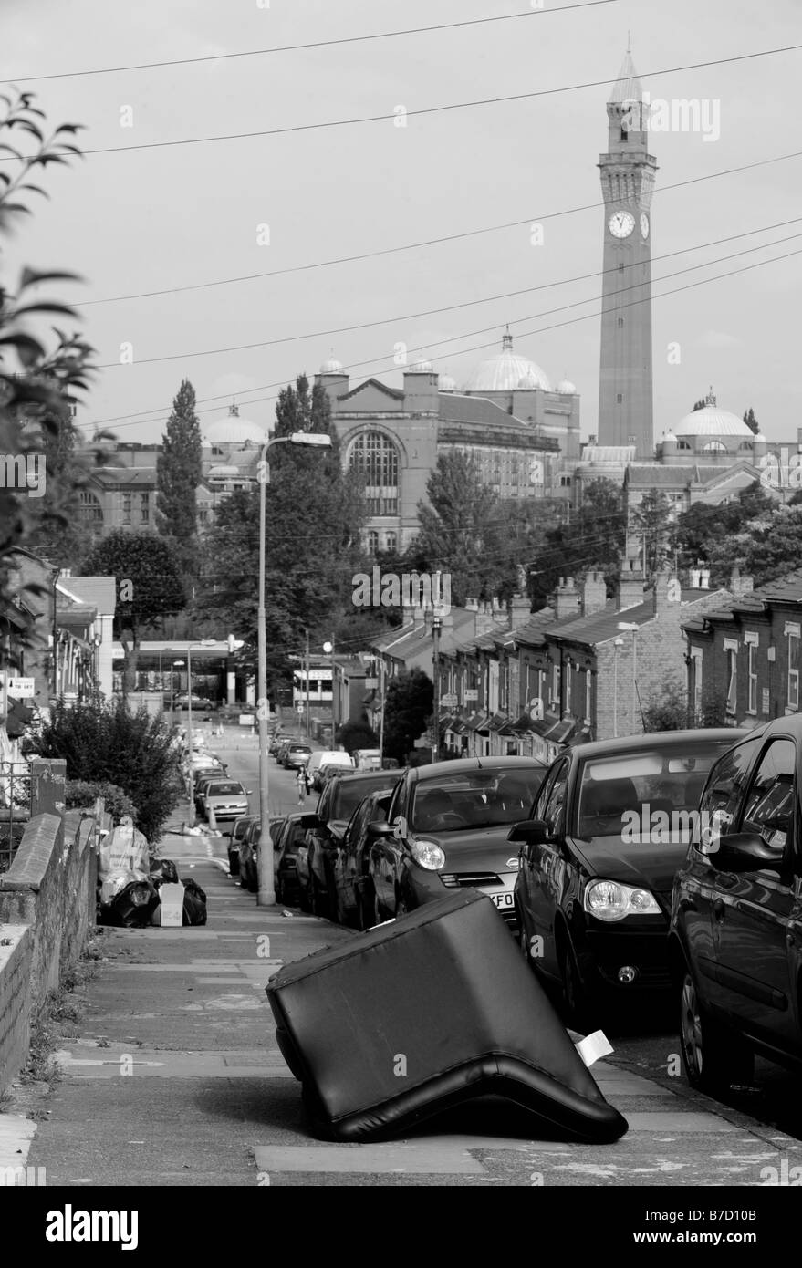 An abandoned sofa on a pavement in the student accommodation area of Bournbrook, with the University of Birmingham rear. Stock Photo