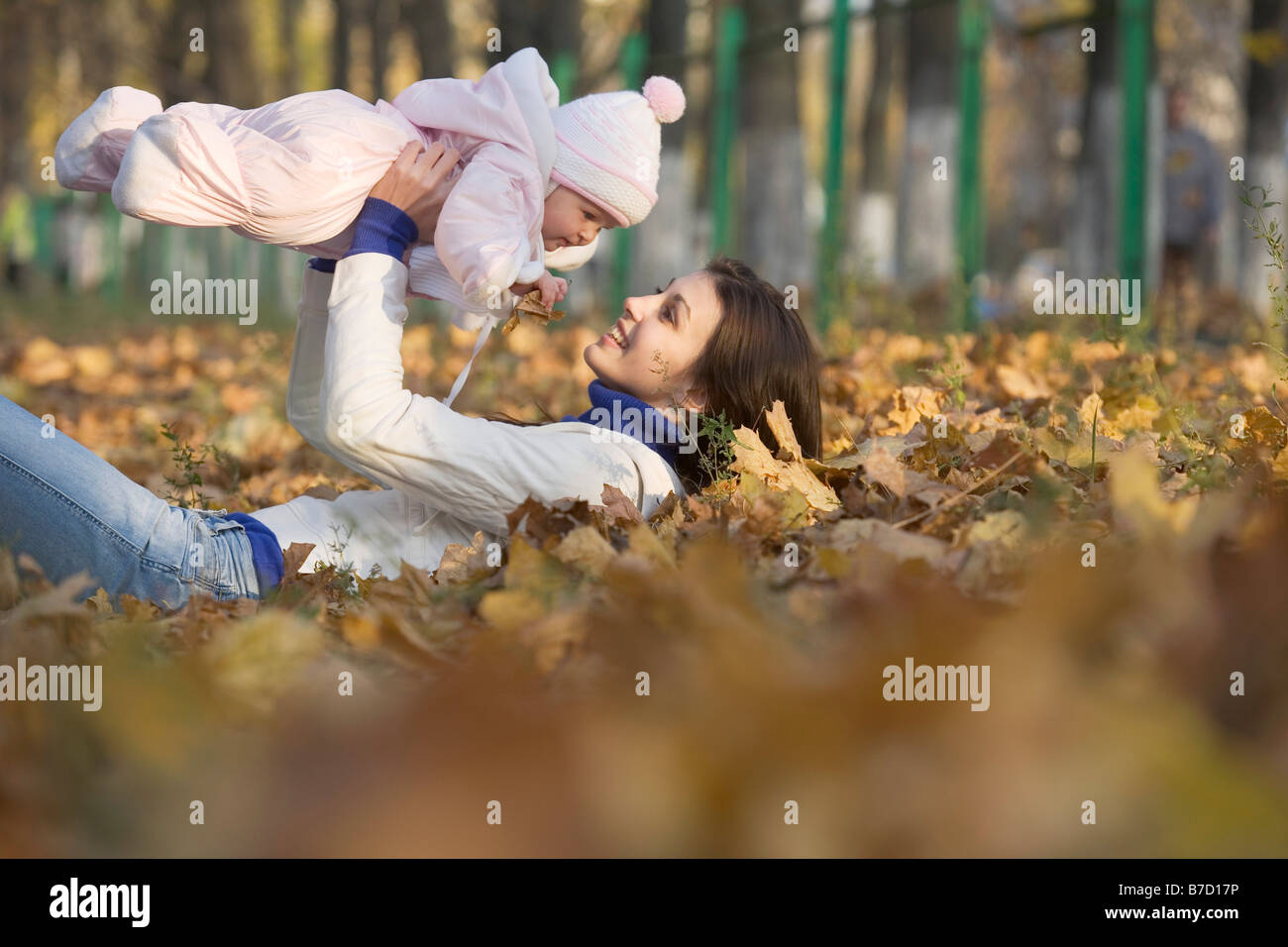 A teenage girl lying down lifting a baby up Stock Photo