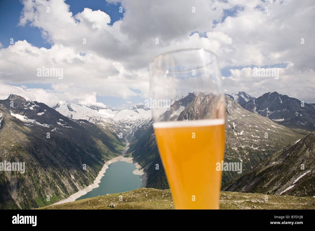 A beer glass in front of a view of the Austrian Alps Stock Photo