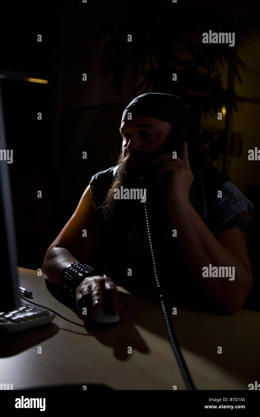 A biker sitting in a darkened office on the phone Stock Photo