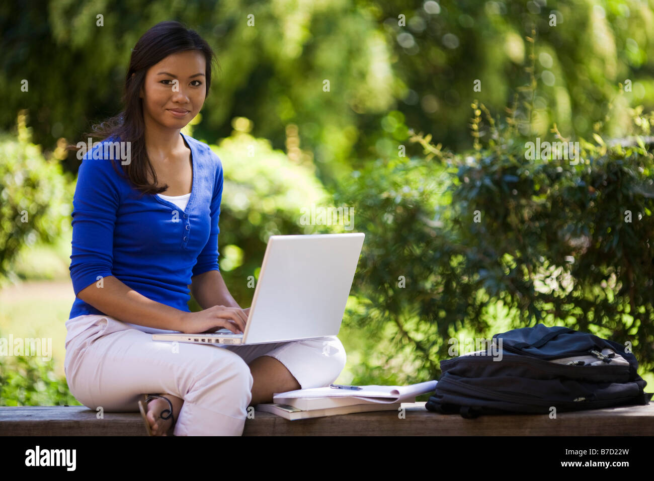 Young woman sitting on a bench with a laptop Stock Photo