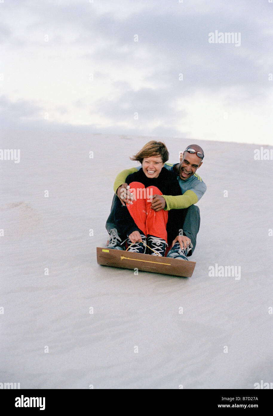 A man and a woman sliding down a sand dune Stock Photo Alamy