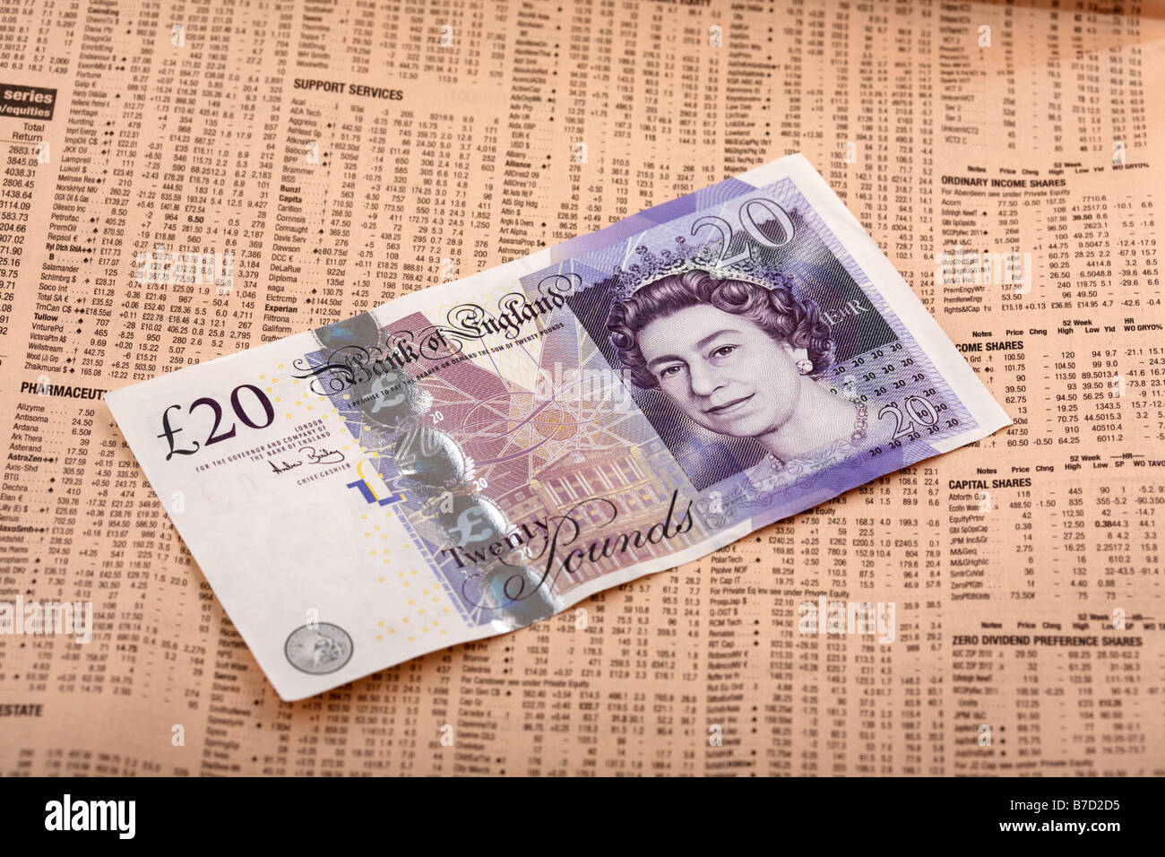 twenty pound note sterling sitting on share information in a copy of the financial times Stock Photo