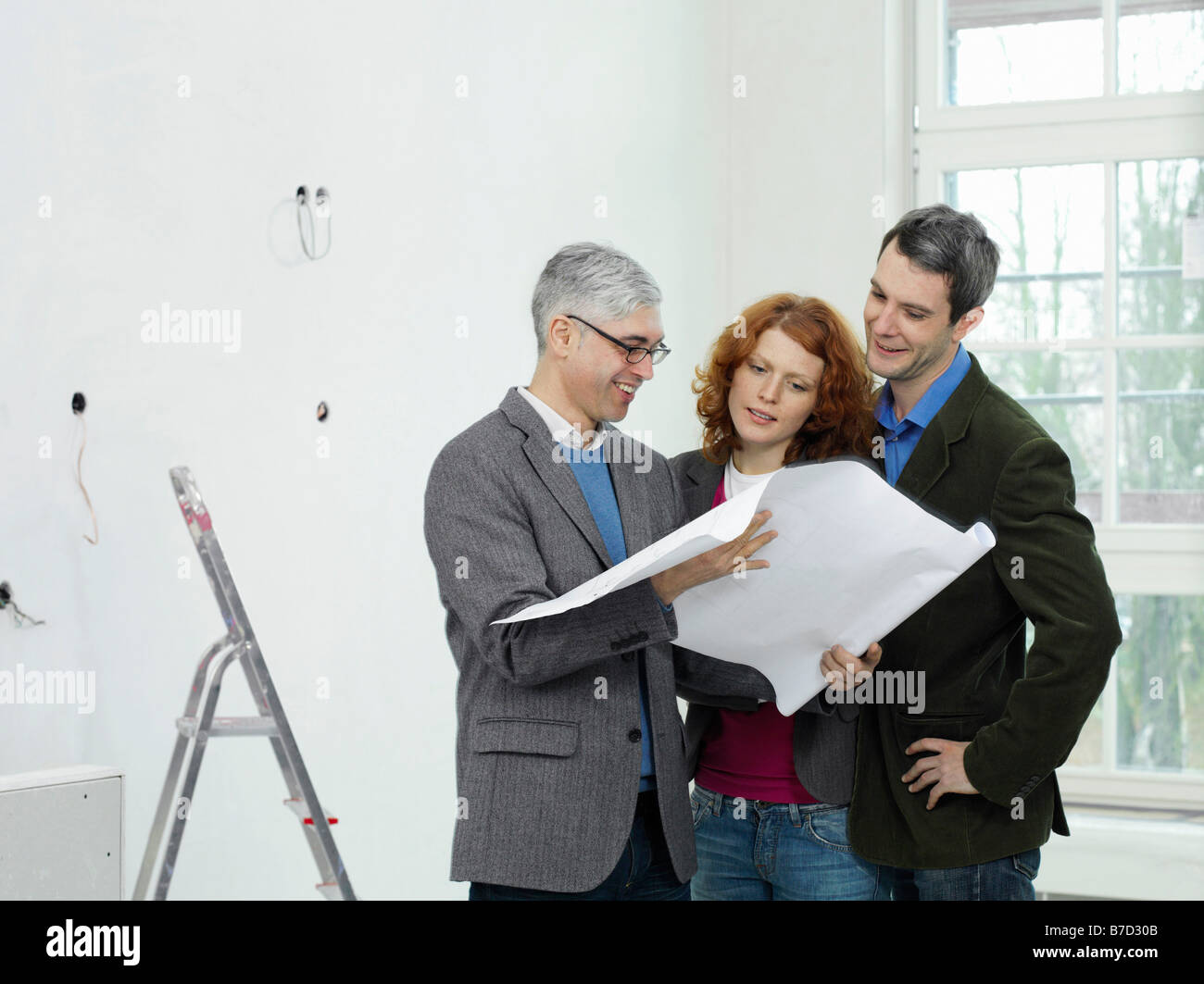 An architect going over blueprints with a young couple Stock Photo - Alamy