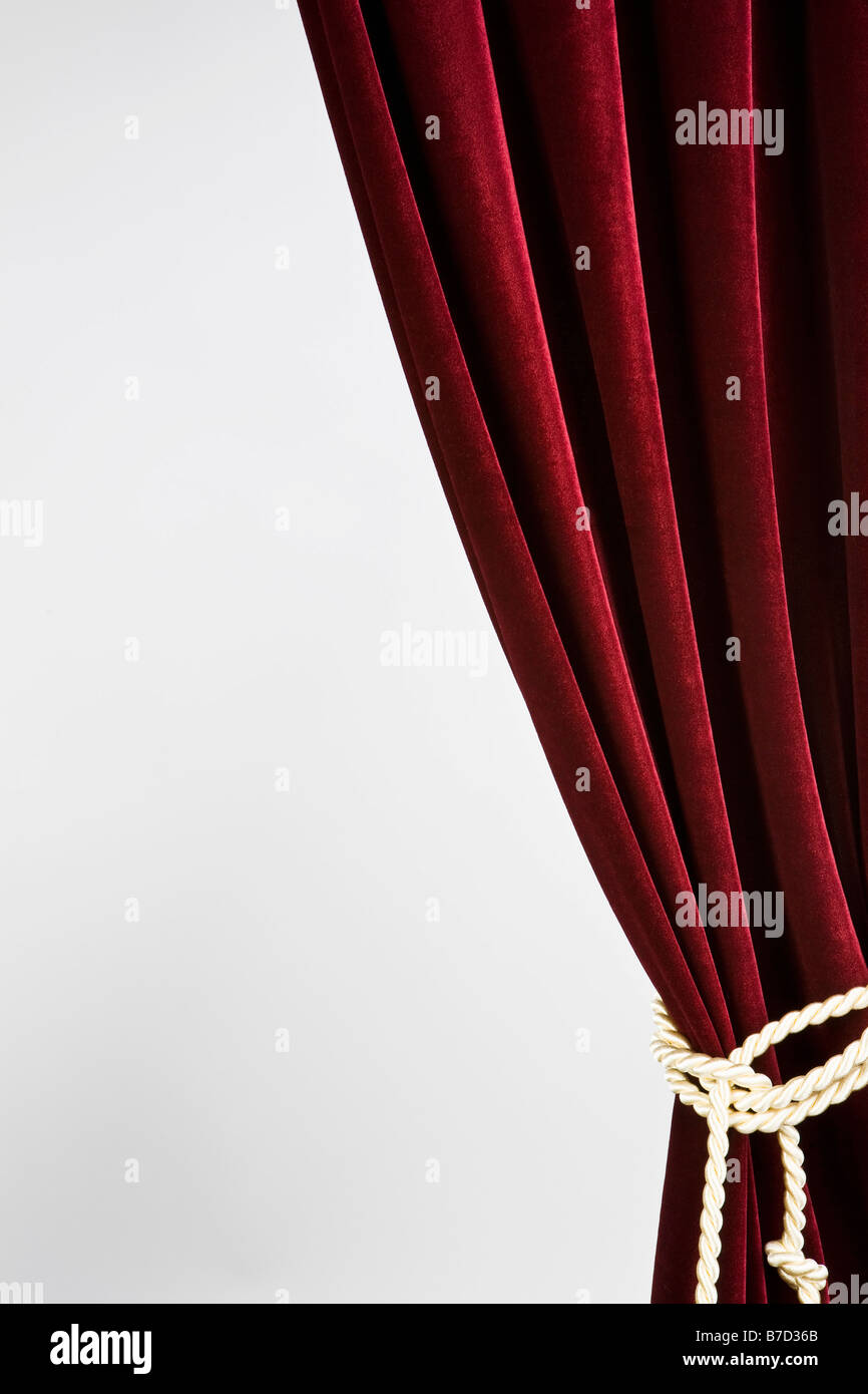 Red velvet curtain tied with a gold rope Stock Photo