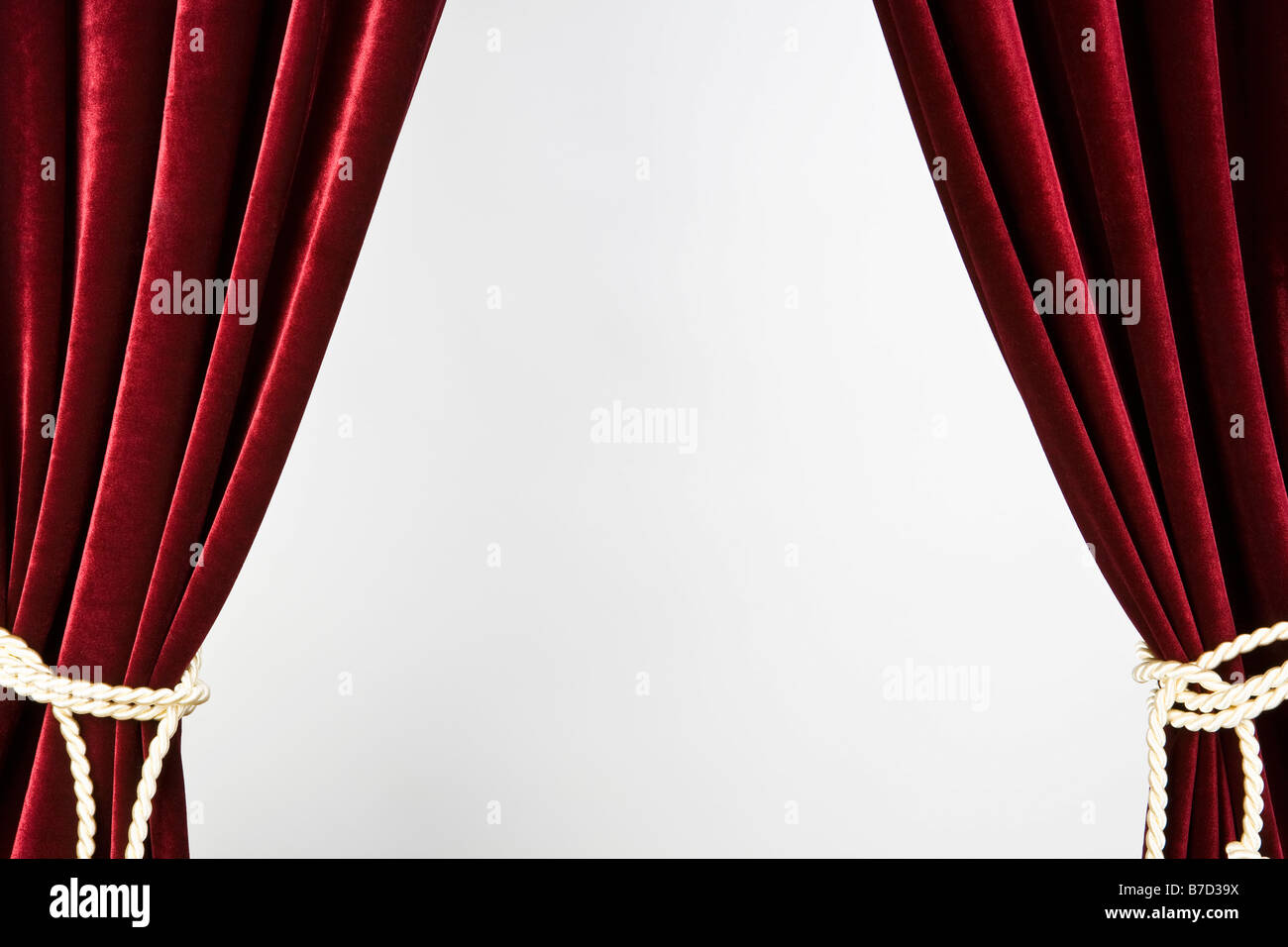 Red velvet curtains tied with gold rope Stock Photo