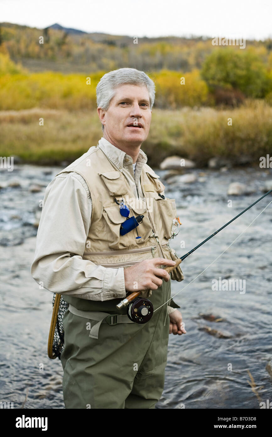 A man standing in a river and holding a fly rod Stock Photo