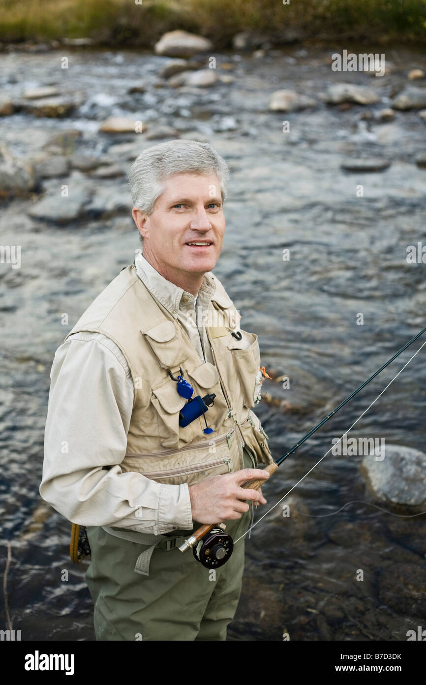 A man standing in a river and holding a fly rod Stock Photo