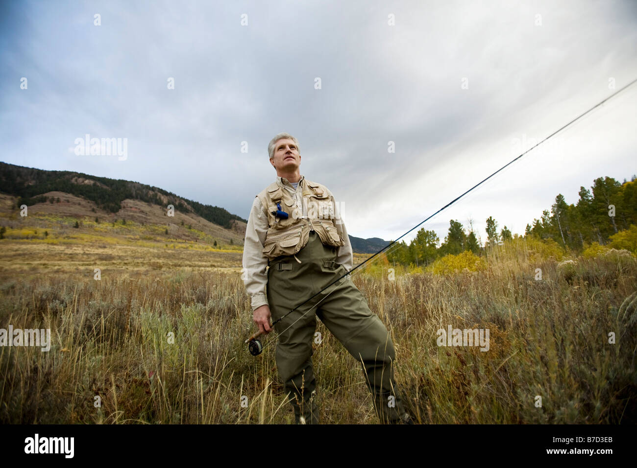 A man standing in a field with a fly rod Stock Photo