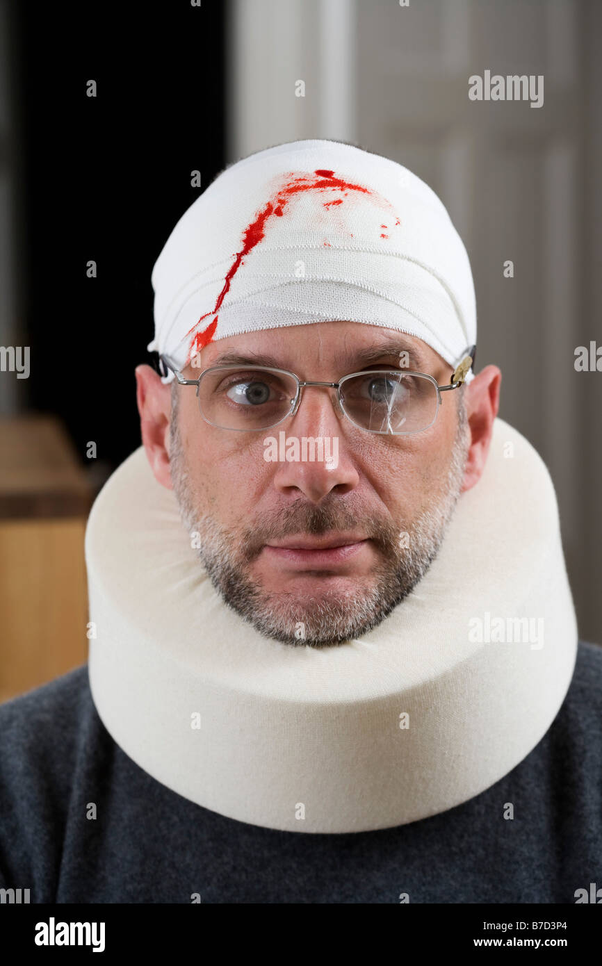 A man wearing cracked glasses, a bloody bandage on his head and a neck brace Stock Photo