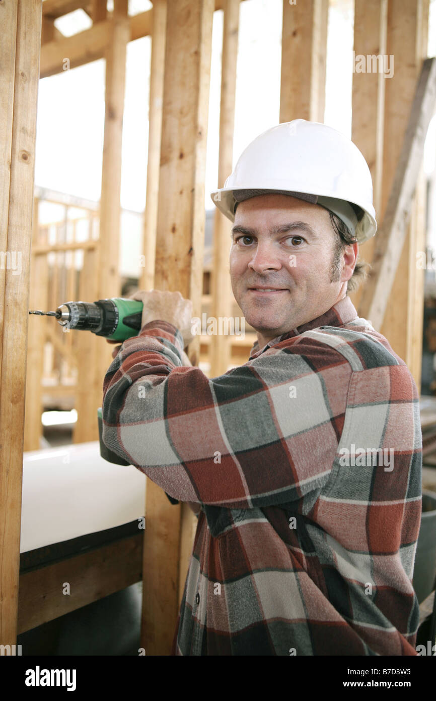 A friendly carpenter drilling on a construction site Vertical view with