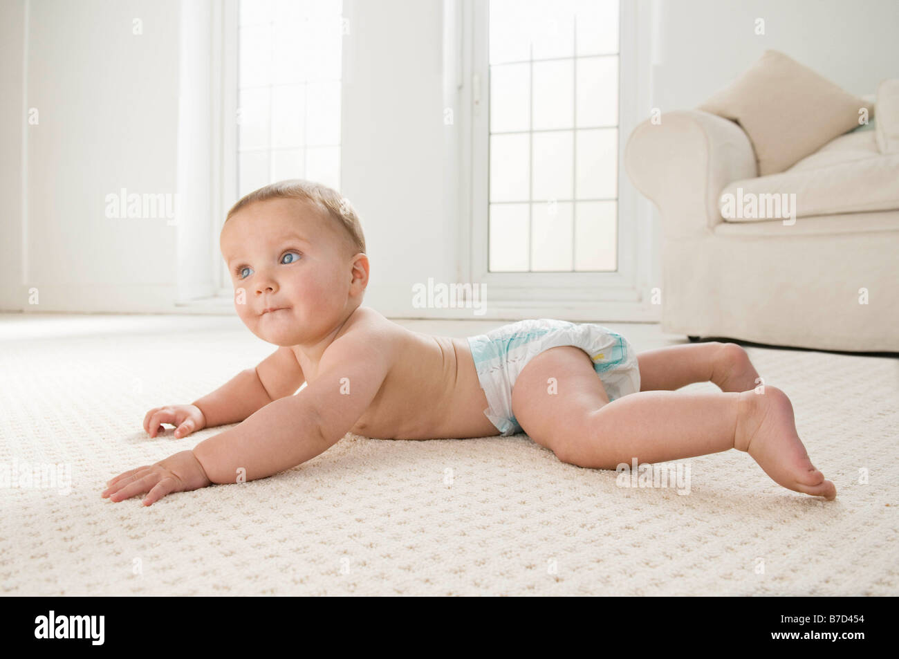 A baby lying on the lounge carpet. Stock Photo