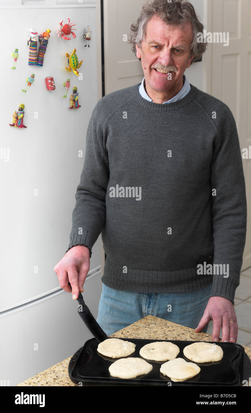 Man in the Kitchen with spatula and pancakes on a griddle Stock Photo