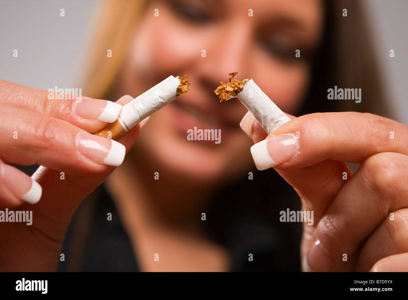 Close up of woman breaking cigarette with her hands focus on cigarette Stock Photo