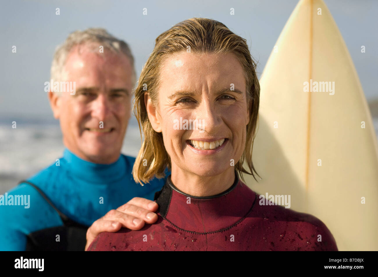 Couple wearing wetsuits on a beach Stock Photo Alamy